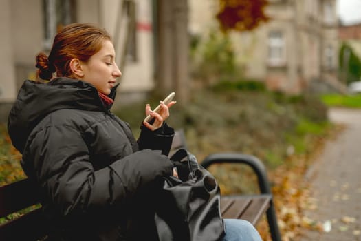 Girl Sitting On A Bench Talking On The Phone In Spring Park