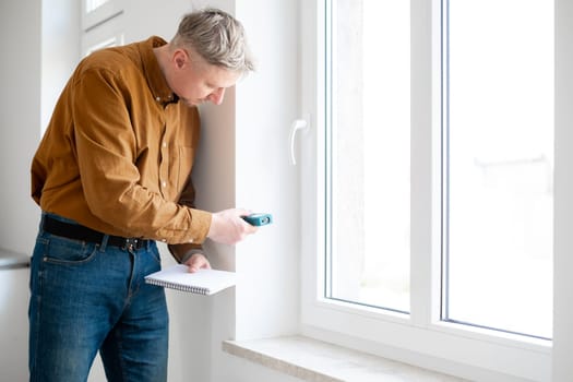 Man Measuring Window Opening With A Special Instrument