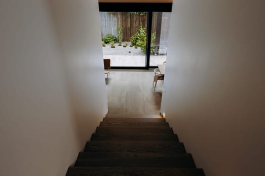 There is a set of wooden stairs that leads up to a window in a residential house, allowing light to flood into the interior space
