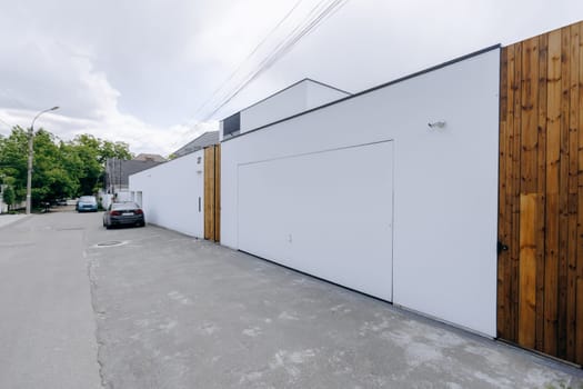 A white building featuring a wooden fence and a car that is parked right in front of it, creating a nice visual appeal