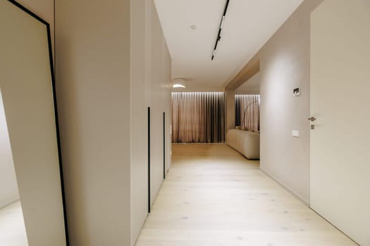 There is a long, spacious hallway featuring a large mirror mounted on the wall alongside a door, adding depth and style to the space