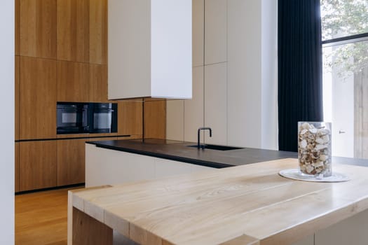 In a cozy kitchen, there is a beautiful wooden table adorned with a lovely vase filled with assorted nuts resting on top of it