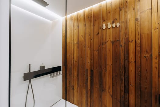 A bathroom that features a beautiful wooden wall along with a modern shower stall designed for comfort and convenience