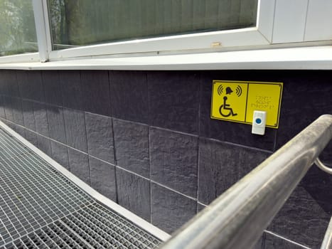 Barrier free access ramp with assistive call button and Braille signage, providing inclusive entry for wheelchair users and people with limited mobility in modern urban buildings