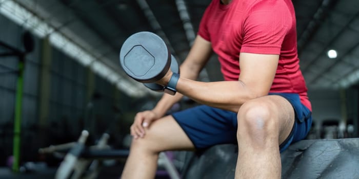An individual engages in strength training with a dumbbell while seated, promoting wellness and physical fitness.