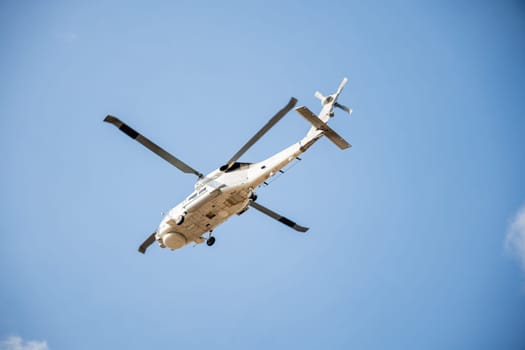 Helicopter in flight against blue sky demonstrating modern rescue and transport technology. New engine hovering capabilities. Pilot maneuvers small aircraft's speed and angles.