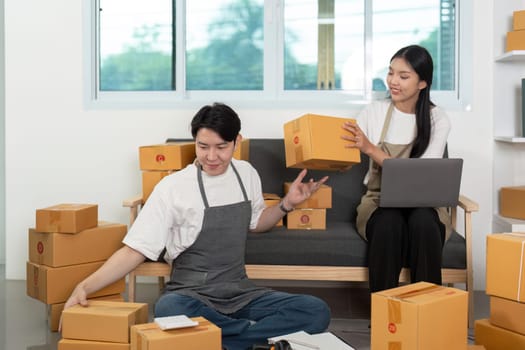 A couple joyfully managing packages together, highlighting teamwork and creativity in their home office.