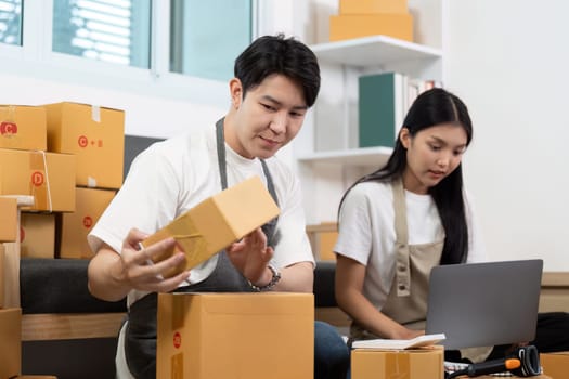 A couple sorts packages and manages their online store inventory in a cozy home office. Emphasizing teamwork in entrepreneurship.