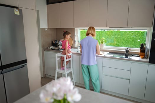 Mother and child enjoy cooking in a sunny kitchen.