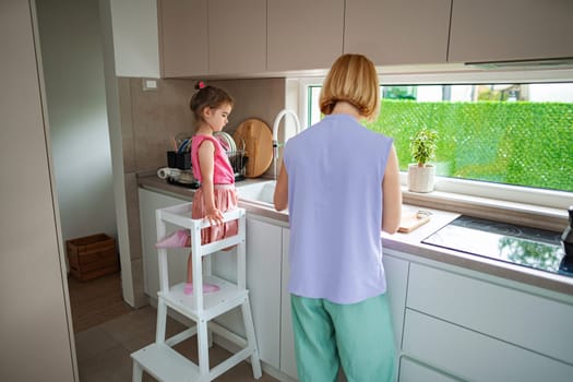A young girl watches closely while her mother prepares food.