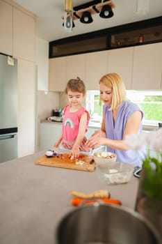 A mother and daughter share joy while preparing food together.