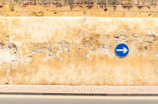 Cracked wall with a safety sign on it, proceed right only.