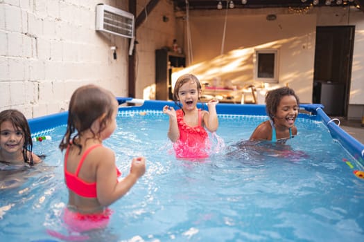Four kids splash and play joyfully in an inflatable pool outdoors.