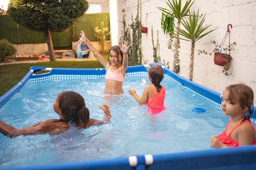 Children are splashing water joyfully in a backyard swimming pool.