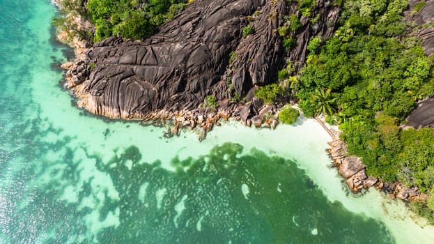 A stunning fusion of granite cliffs and turquoise waters framed by lush greenery and white sands. Praslin, Seychelles.