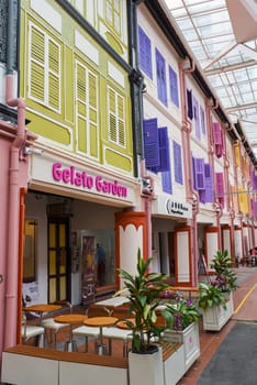 Singapore, Singapore - 4 April 2025: Colorful shophouses with shuttered windows in Little India, featuring a gelato cafe and vibrant street decor.
