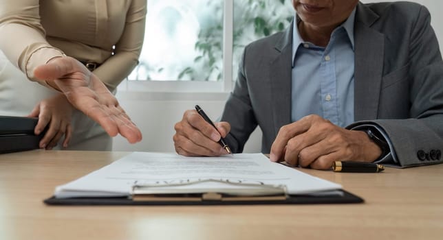 A businessman reviews and signs important documents, showcasing professionalism and commitment in a corporate setting.