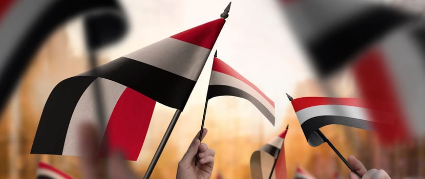 Yemen flags in their hands on a blurred urban background. The photo illustration was created without the use of artificial intelligence, only using Photoshop.
