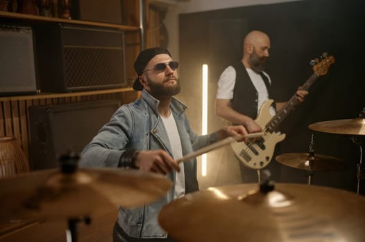 Rock band performance. Focus on stylish male drummer beating music rhythm on drum with sticks