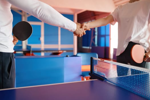 Two table tennis player shaking hands greeting each other with successful friendly match cropped shot