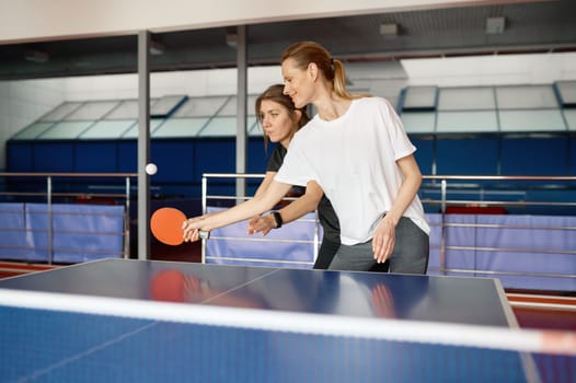 Adult woman instructor teaching female student play table tennis. Sports life concept