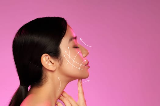 A woman is engaged in facial massage, highlighted by arrows illustrating the technique on her profile. The vibrant pink background adds a lively contrast to the scene.