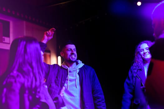 A group of friends socializes in a lively nightlife setting, with vibrant lighting creating an energetic atmosphere. Laughter and conversation fill the air as they enjoy the evening.