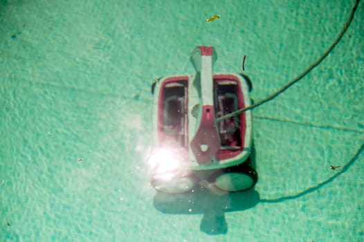 Automatic robotic pool vacuum cleaner under water cleaning the floor. view through water. High quality photo