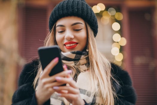 Close-up shot of woman hands with smartphone in the city. Close shot on hands using phone during winter time. Technology, winter and holiday concept.
