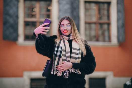 Making selfie with smartphone. Portrait beautiful girl making selfie photo on smartphone at street. Sexy woman photographing in luxury clothing outdoor. Woman taking self portrait near city street.
