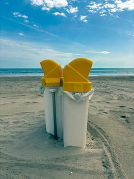 Yellow trash containers on the beach. The concept of the environment and separate waste collection.