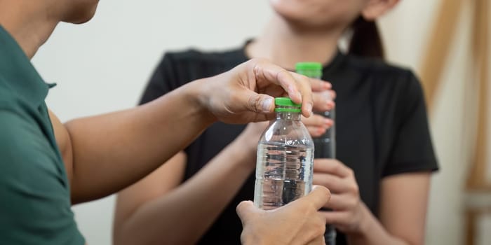 A couple enjoying their fitness routine, sharing water bottles while staying hydrated and motivated together.
