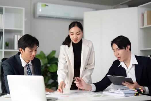 A diverse team of professionals collaborates on a project, reviewing charts and strategies in a contemporary office environment, emphasizing teamwork and communication.