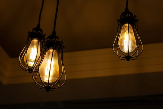 In a dimly lit room, three light bulbs are suspended from the ceiling, casting a warm glow to illuminate the darkness surrounding them