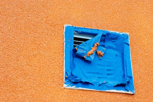 There is an orange wall that features a blue square painted prominently on its surface, adding a vibrant contrast to the setting