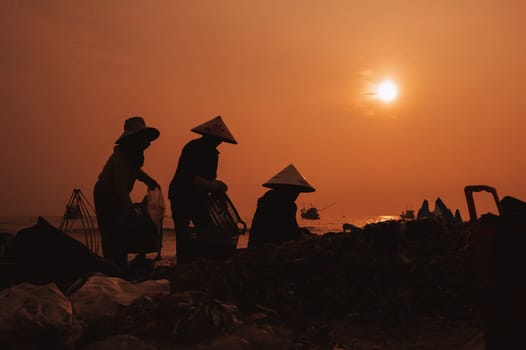 Silhouettes of Vietnamese women at a Fish Market Tam Tien o the coast in a fishing village in the morning at sunrise in Vietnam. Tam Tien, Quang Nam province, Vietnam - April 10, 2025