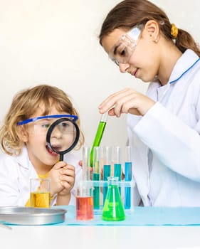 Laboratory examination of a child with test tubes, reagents and a microscope. Selective focus. kid.