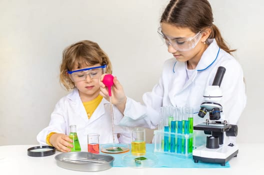 Laboratory examination of a child with test tubes, reagents and a microscope. Selective focus. kid.