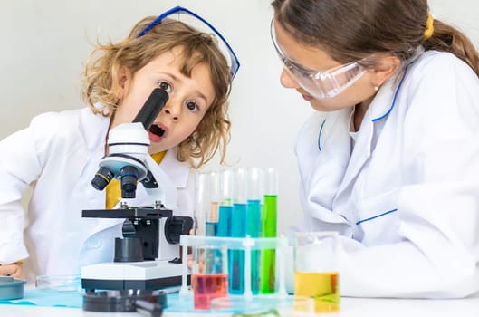 Laboratory examination of a child with test tubes, reagents and a microscope. Selective focus. kid.