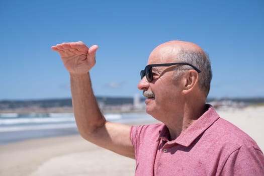 Elderly Man with Mustache and Sunglasses Looking into the Distance over the Ocean.Travel and Tourism in Retirement