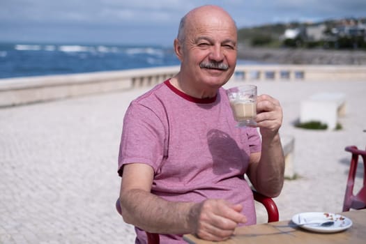 Elderly Man with Mustache Drinking Coffee at Outdoor Cafe on Vacation near sea