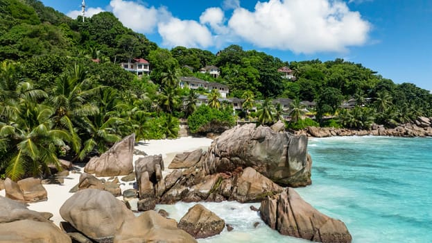 Tropical beachfront resort with turquoise waters, lush greenery, and white sand. Anse Patates, Seychelles.