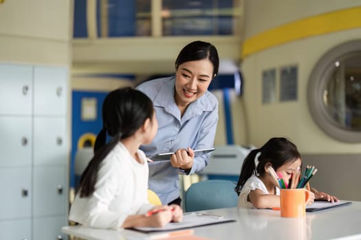 A teacher supports two girls as they engage in learning activities, promoting a positive back-to-school experience.