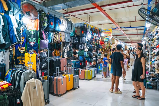 A lively passage of the indoor clothing market with suitcases, bags and other clothing items on display. Nha Trang, Vietnam - December 13, 2024