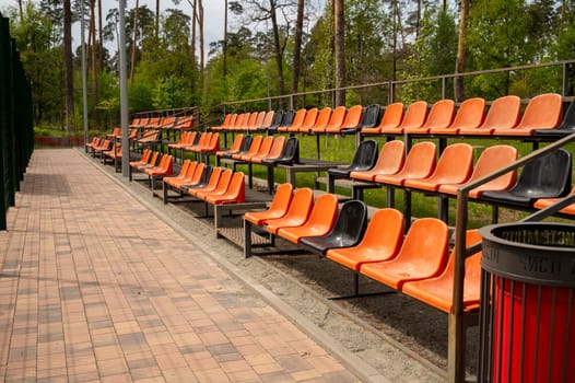 Rows of empty orange plastic seats on the grandstand near the outdoor sports stadium. grandstand for sport conceptual background. High quality photo