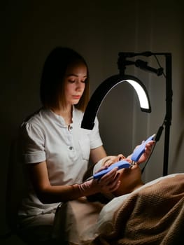 Cosmetic procedure for a woman Microcurrents for a woman's face at a beautician. Rejuvenating effect, toned skin, uniform skin color. Close-up, vertical