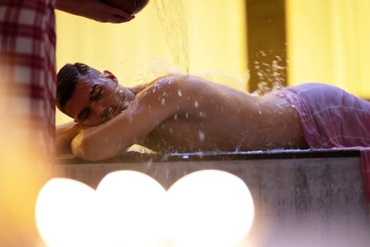 Water Treatment in Turkish Hammam.Man receiving water therapy inside a traditional Turkish hammam with ornate details.