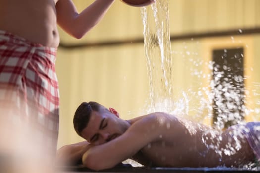 Water Treatment in Turkish Hammam.Man receiving water therapy inside a traditional Turkish hammam with ornate details.