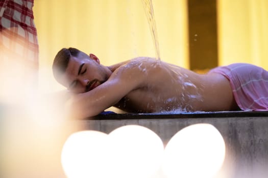 Water Treatment in Turkish Hammam.Man receiving water therapy inside a traditional Turkish hammam with ornate details.