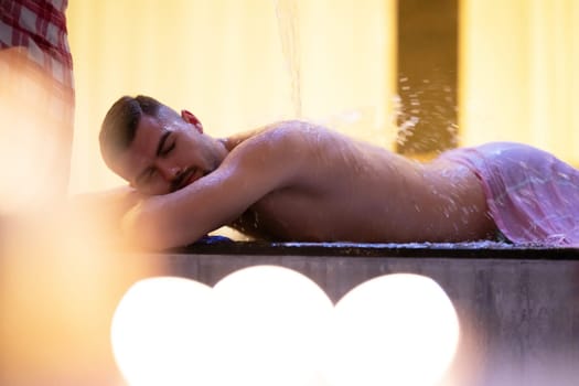 Water Treatment in Turkish Hammam.Man receiving water therapy inside a traditional Turkish hammam with ornate details.